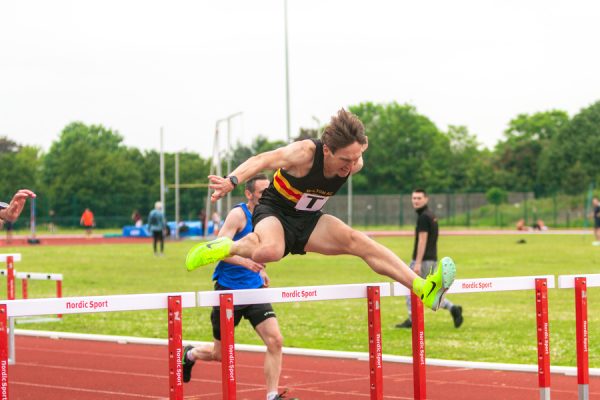 Man jumping over a hurdle on an athletics track