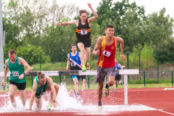 Men jumping the steeple chase water jump