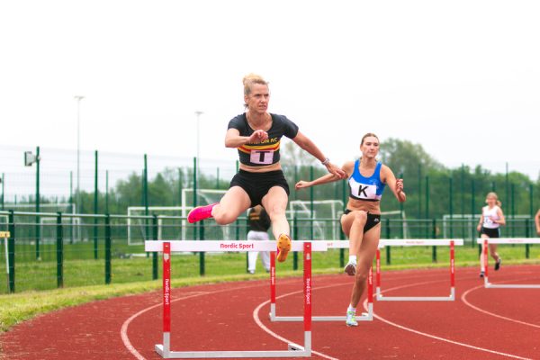Woman jumping over a hurdle on an athletics track