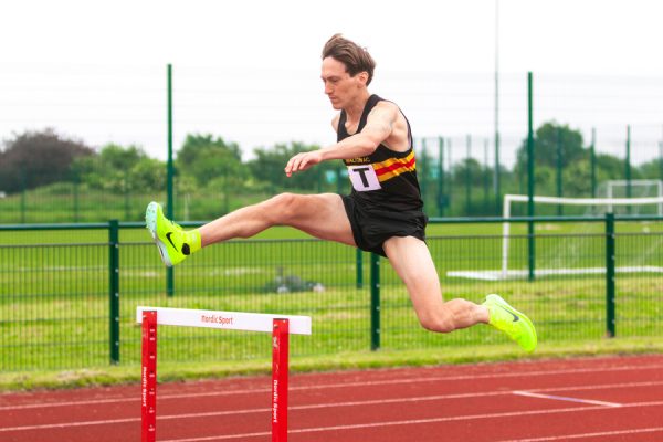 Man jumping over a hurdle on an athletics track