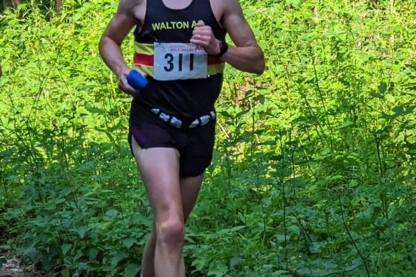 Man in Walton ac vest running on a road