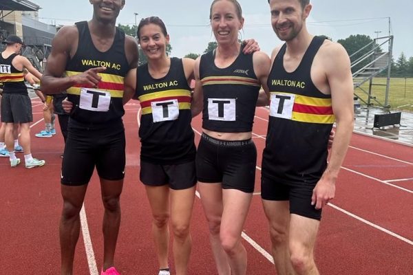 Group of athletes in Walton vests on an athletics track