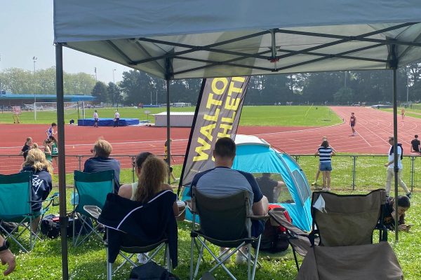 People sitting under a tent next to an athletics track