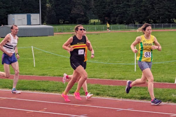 Lady in Walton athletic club vest running on an athletics track