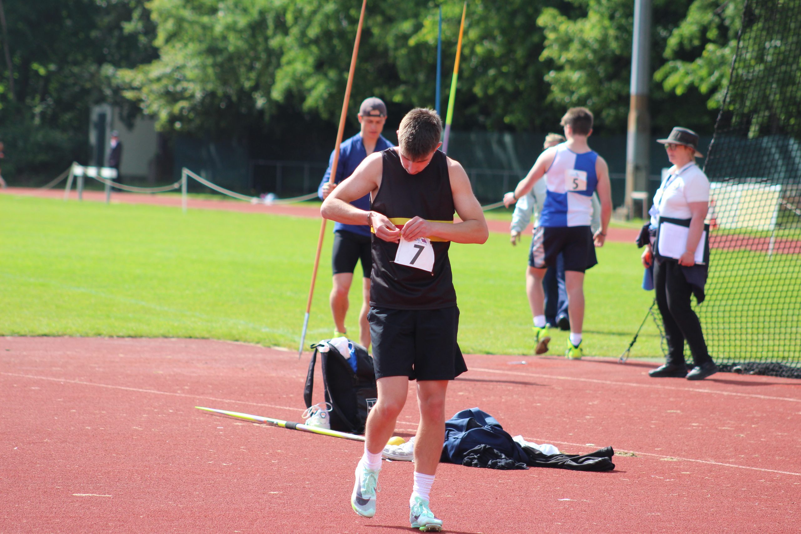 Man pining a number 7 on a black vest while on an athletics track