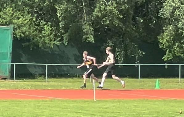 Two men passing a relay baton on an athletics track