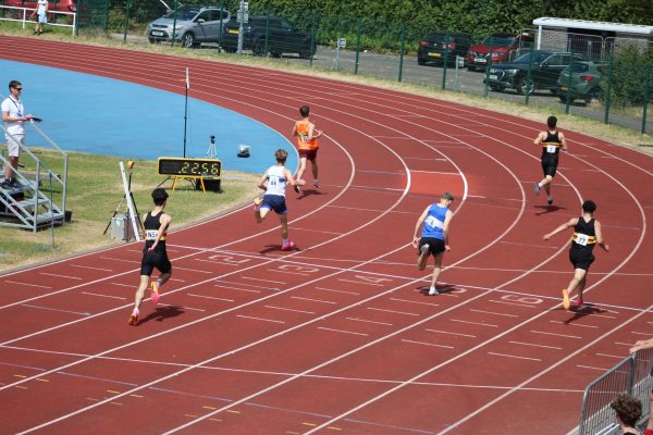 Group of men going over the finish line on an athletics track